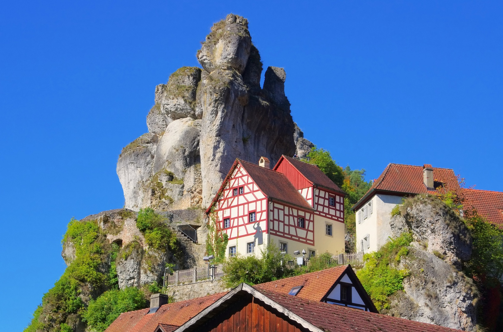 Ein Karstfelsen, auf und an den sich Fachwerkhäuser schmiegen; Detektei Franken