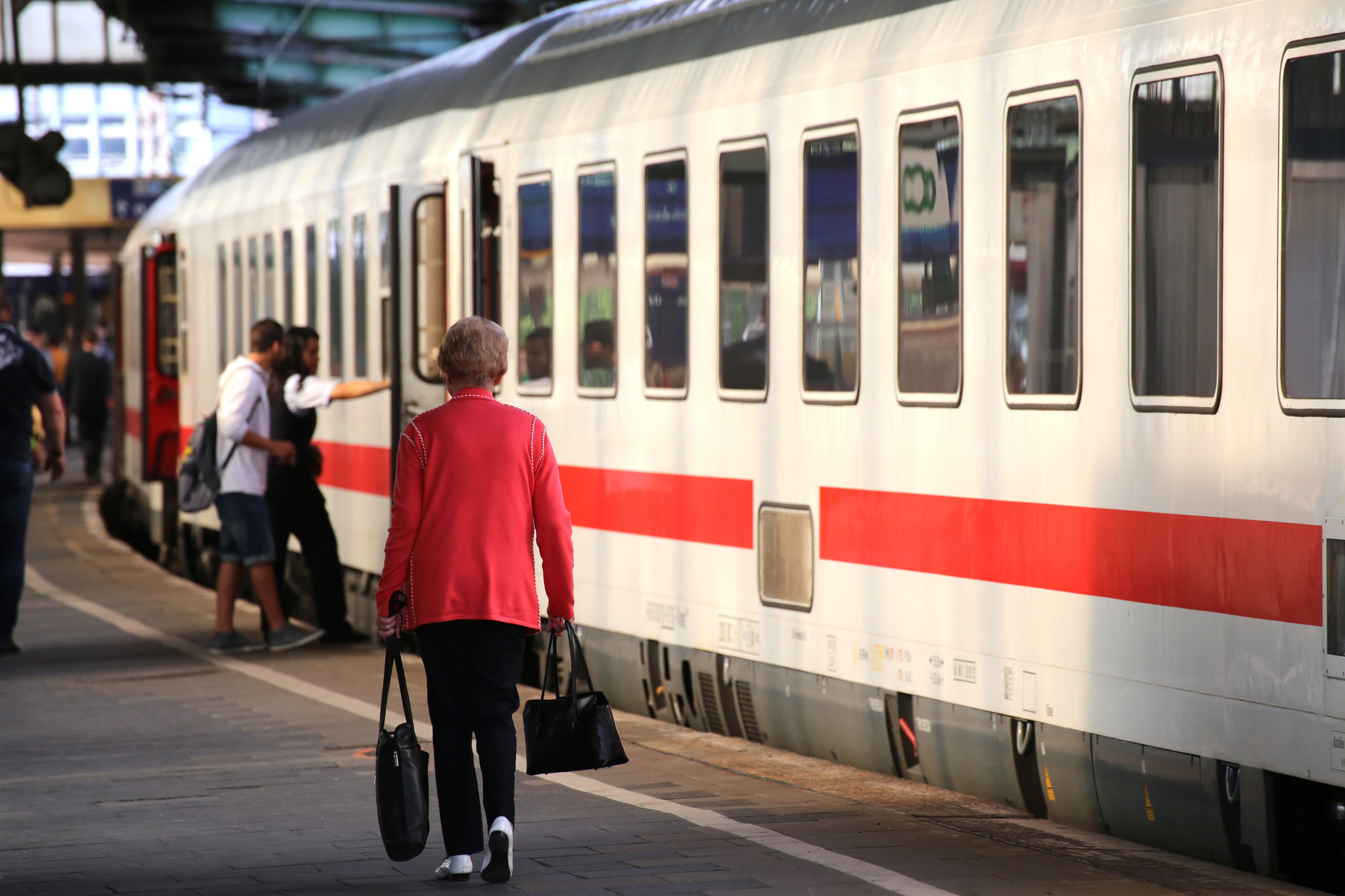 Alte Frau auf einem Bahnsteig mit zwei Handtaschen neben einem wartenden ICE oder IC; Kurtz Detektei Nürnberg